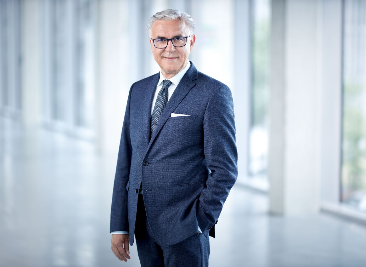 Portrait einer Führungskraft in blauem Anzug mit Einstecktuch, on location in einem hellen Flur des Unternehmens aufgenommen